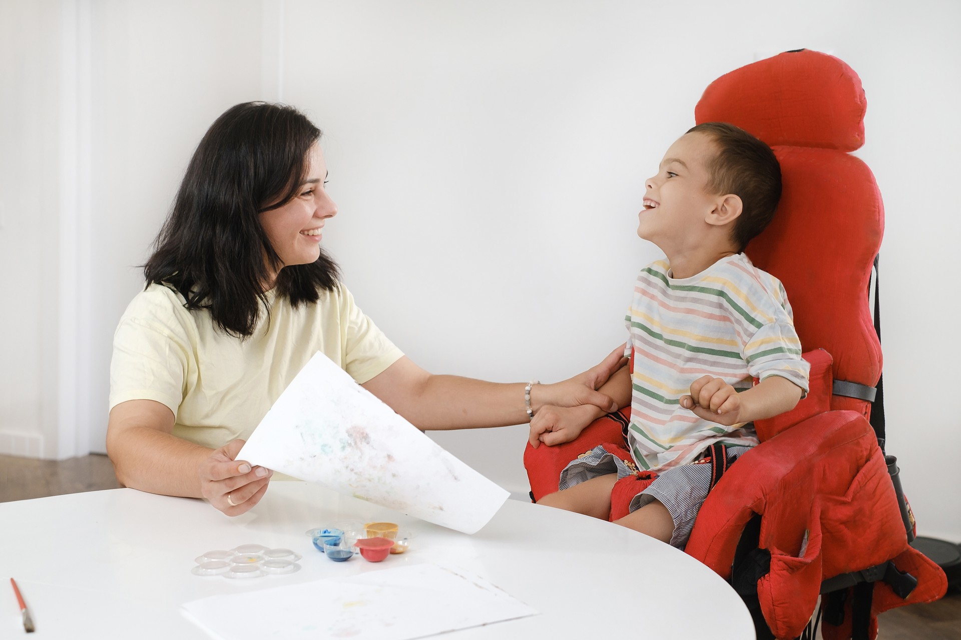 Child with cerebral palsy painting, mental physical problem, sensory therapy